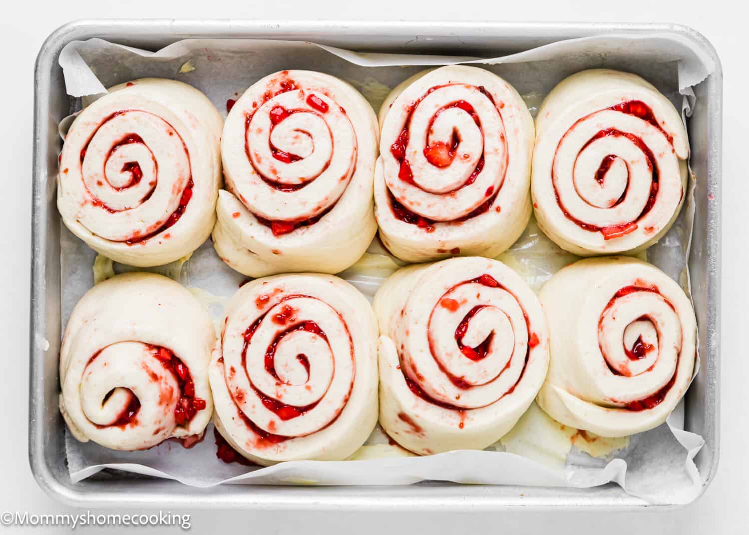 risen unbaked Strawberry Rolls in a baking tray.