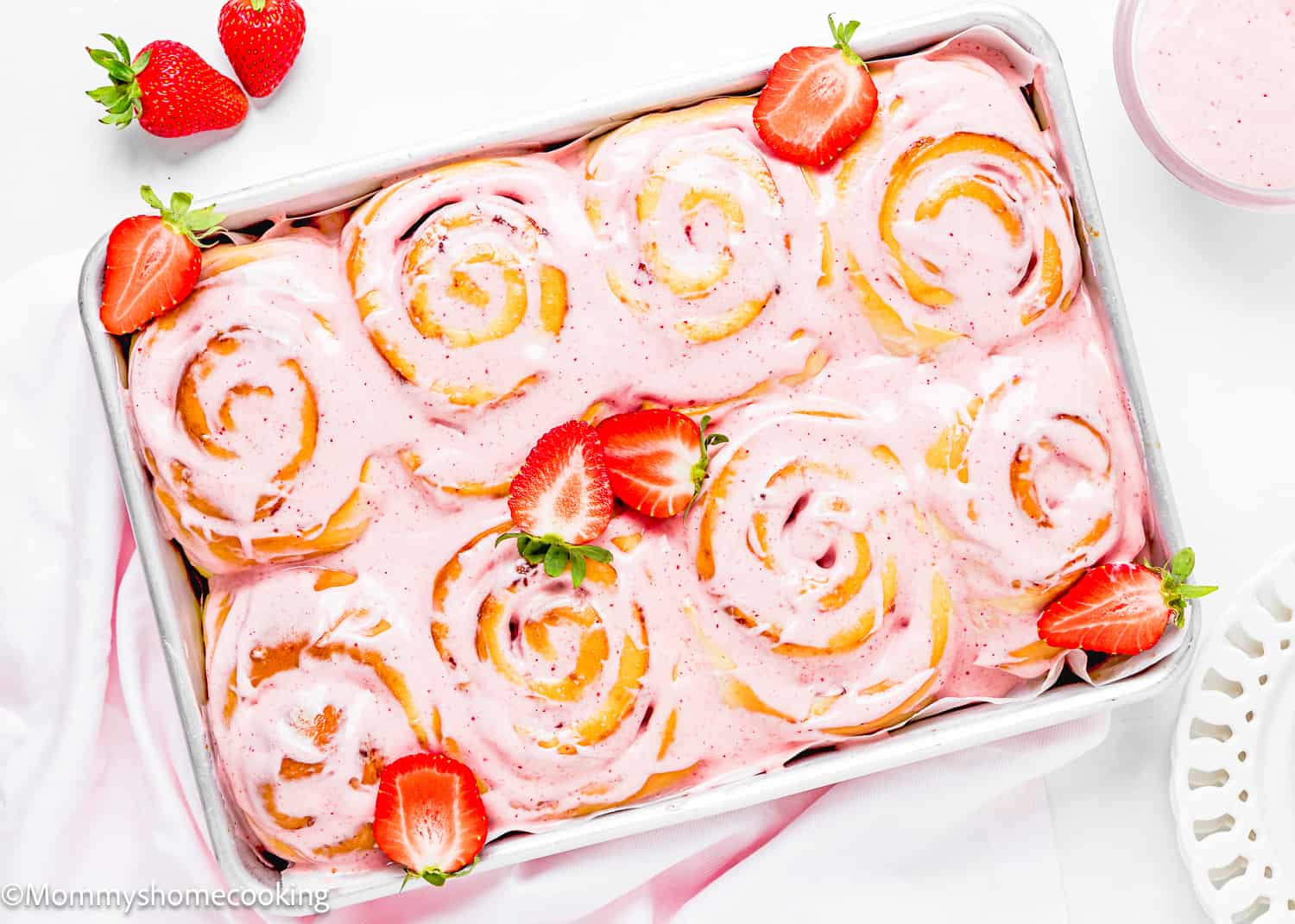 Easy Strawberry Rolls with frosting and fresh strawberries in a baking pan.
