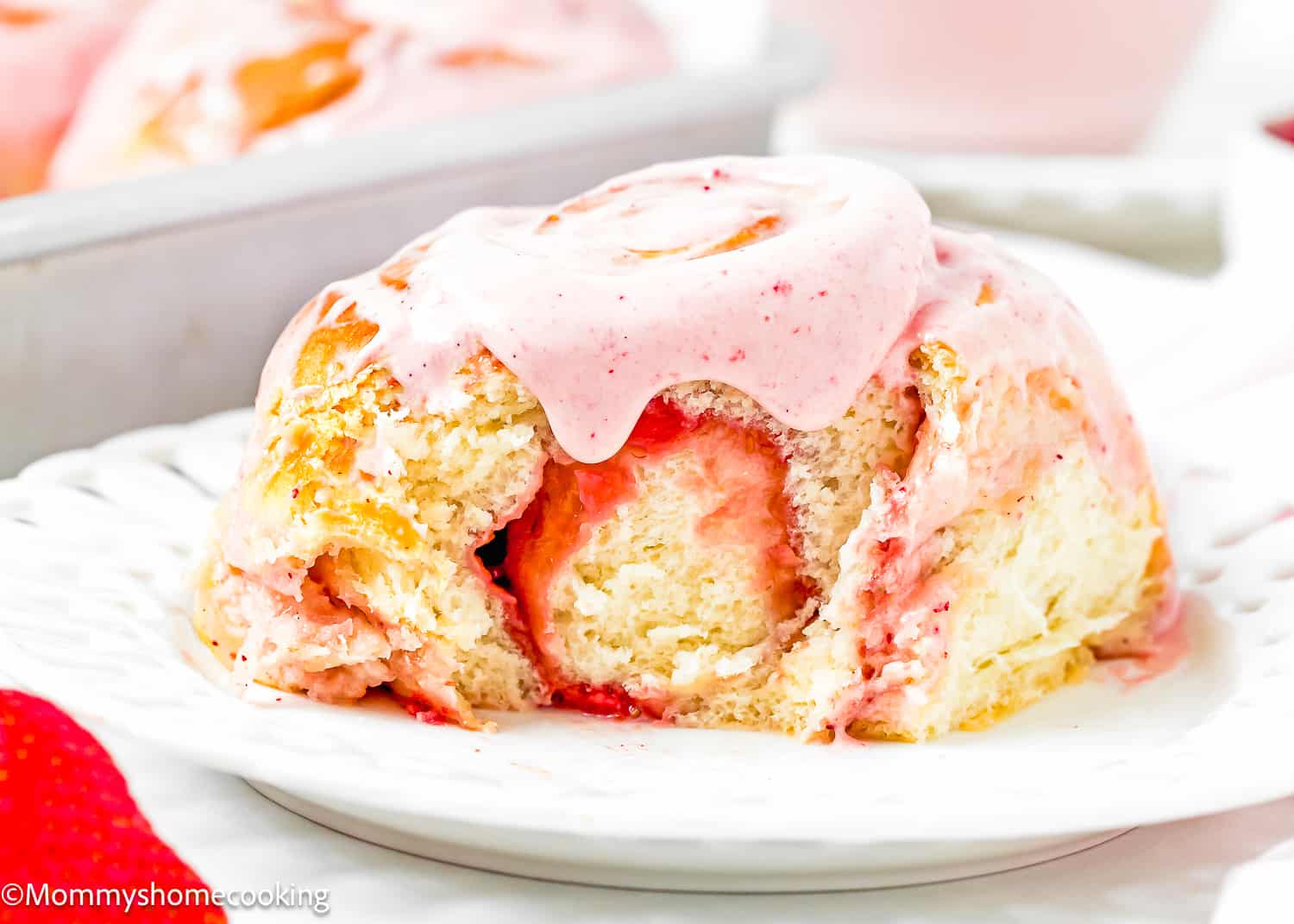 an Easy Strawberry Roll with frosting from on a plate showing its fluffy and tender texture.