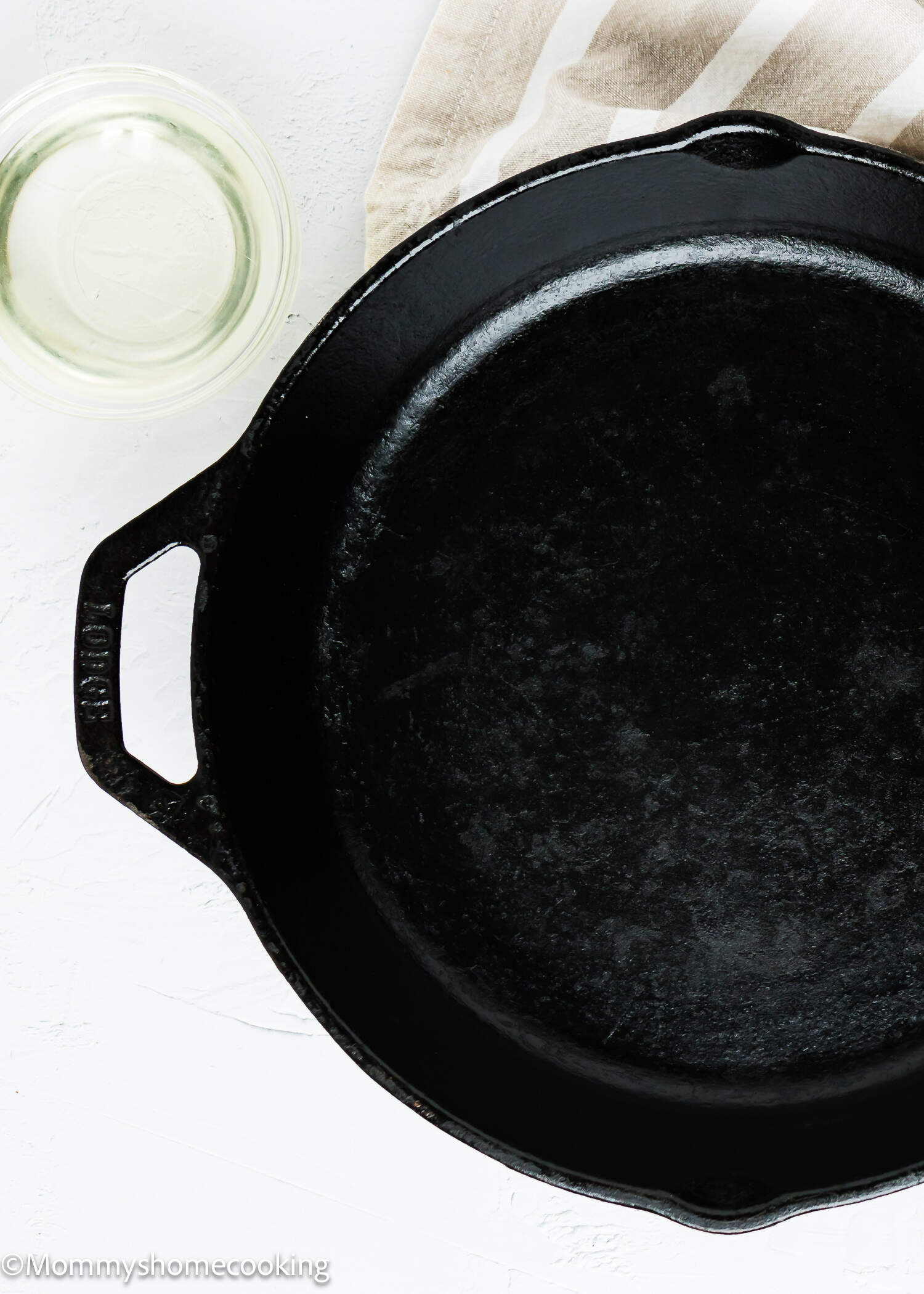a cast iron pan with a container with oil on the side.