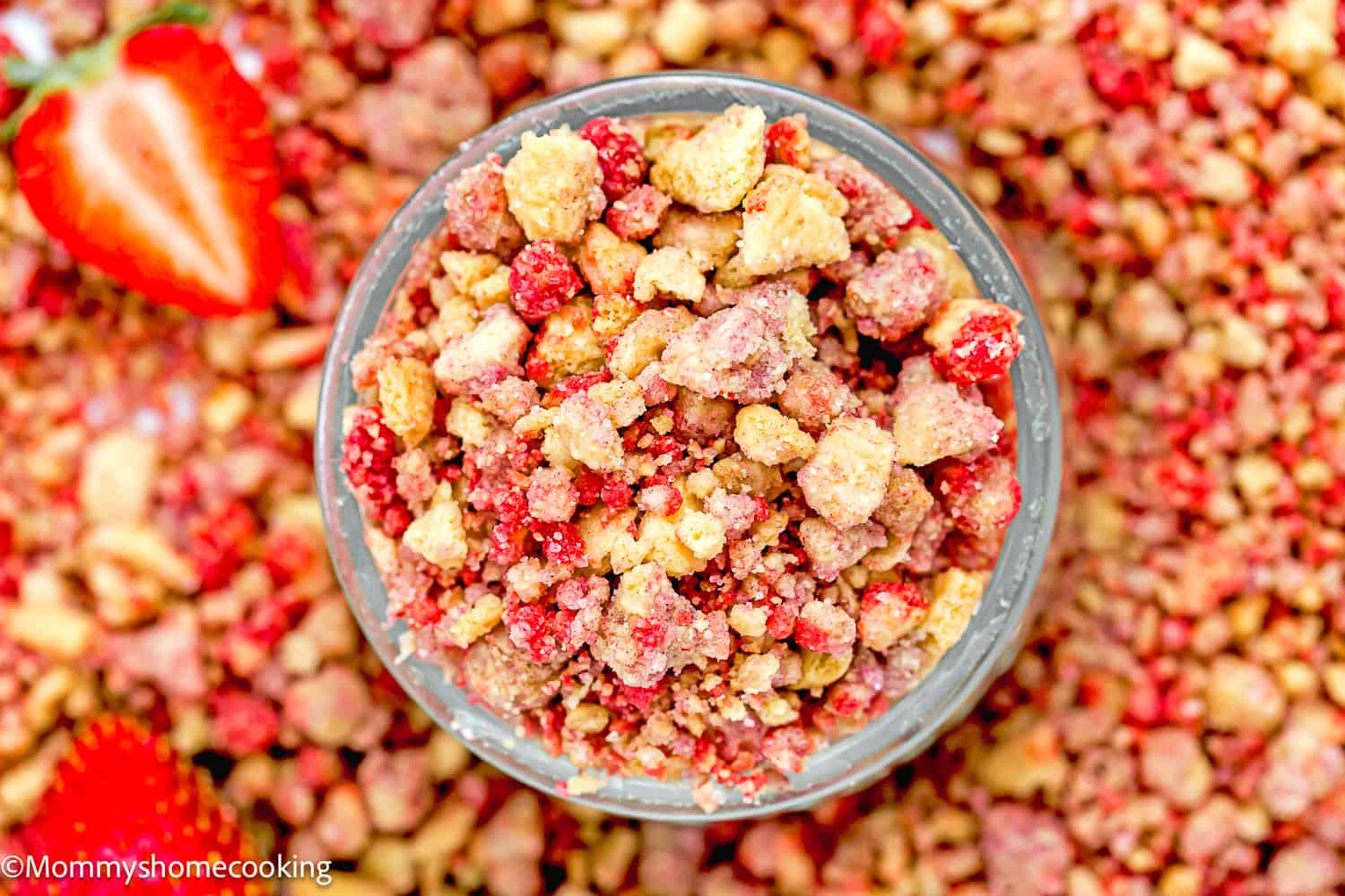 homemade Strawberry Crunch in a small glass bowl with fresh strawberry around it.