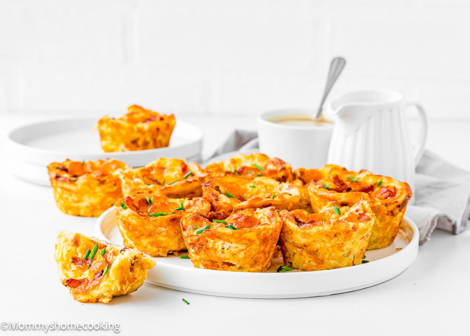 Breakfast Egg Muffins Without Eggs with chopped chives in a plate with a cup of coffee in the background.