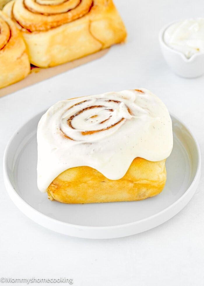 a cinnamon roll in a plate with Cream Cheese Frosting.