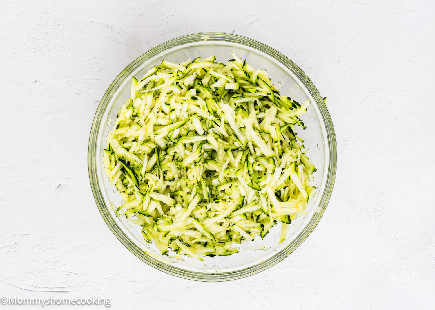 grated zucchinis to make Eggless Zucchini Fritters in a bowl.