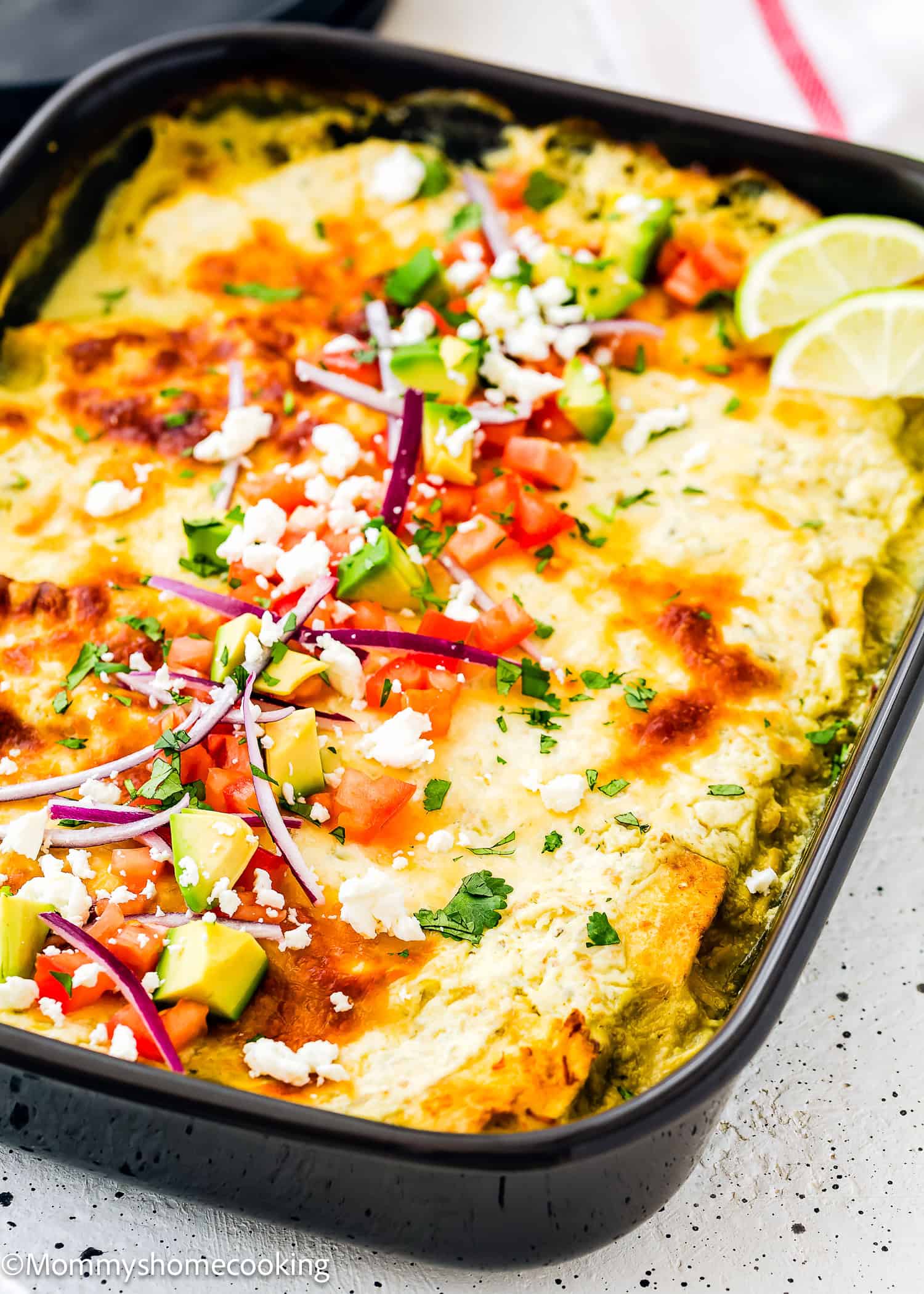 Super Easy Enchiladas Suizas with topping in a black casserole dish.
