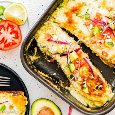Quick and Easy Enchiladas Suizas with topping in a black casserole dish wit more topping on the sides.