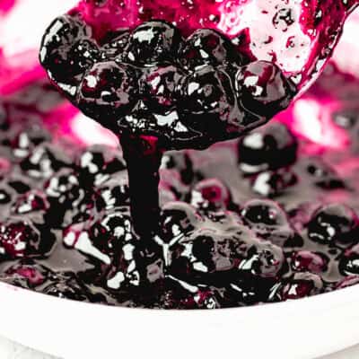 Quick and Easy Homemade Blueberry Sauce Topping in a saucepan with a spoon.
