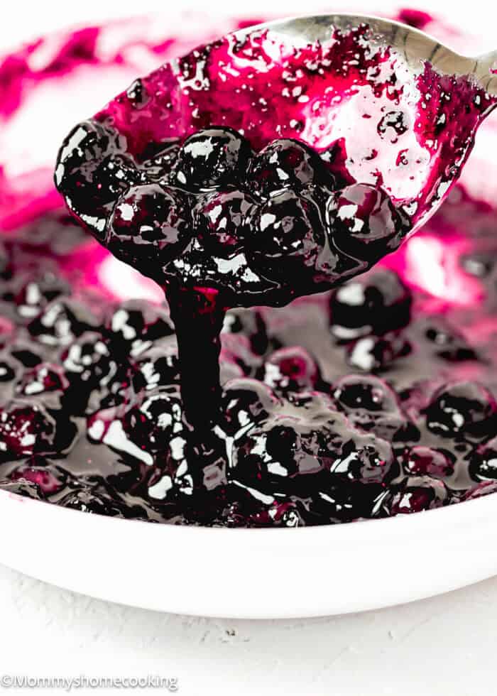 Quick and Easy Homemade Blueberry Sauce Topping in a saucepan with a spoon.