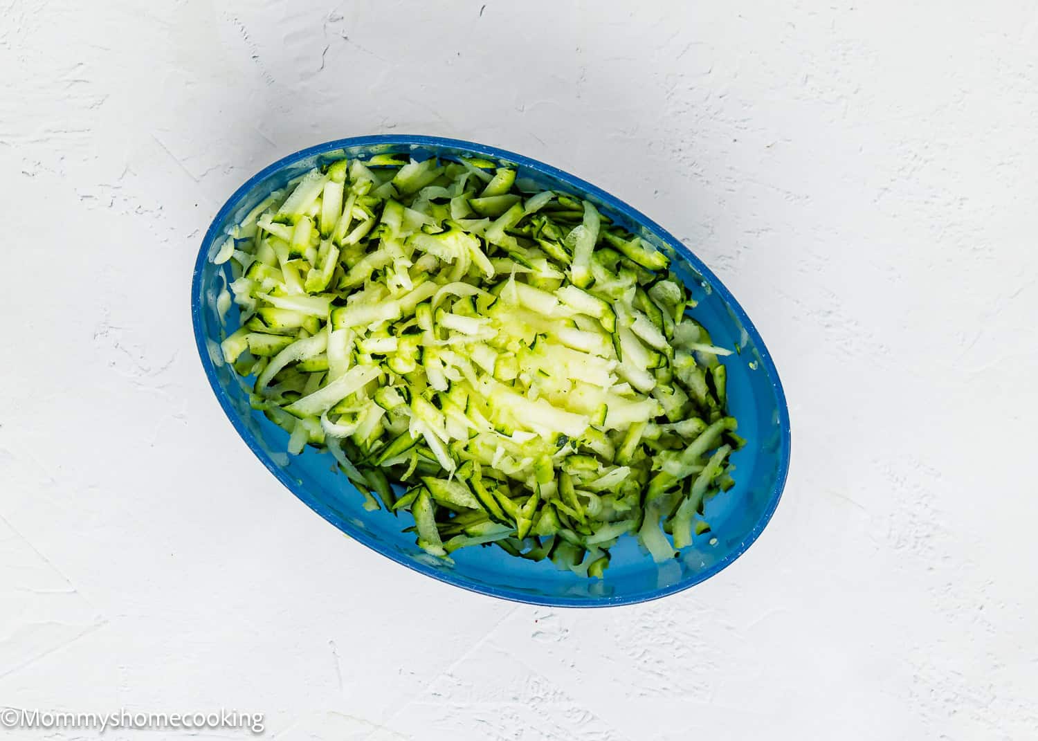 grated zucchini in a blue container.