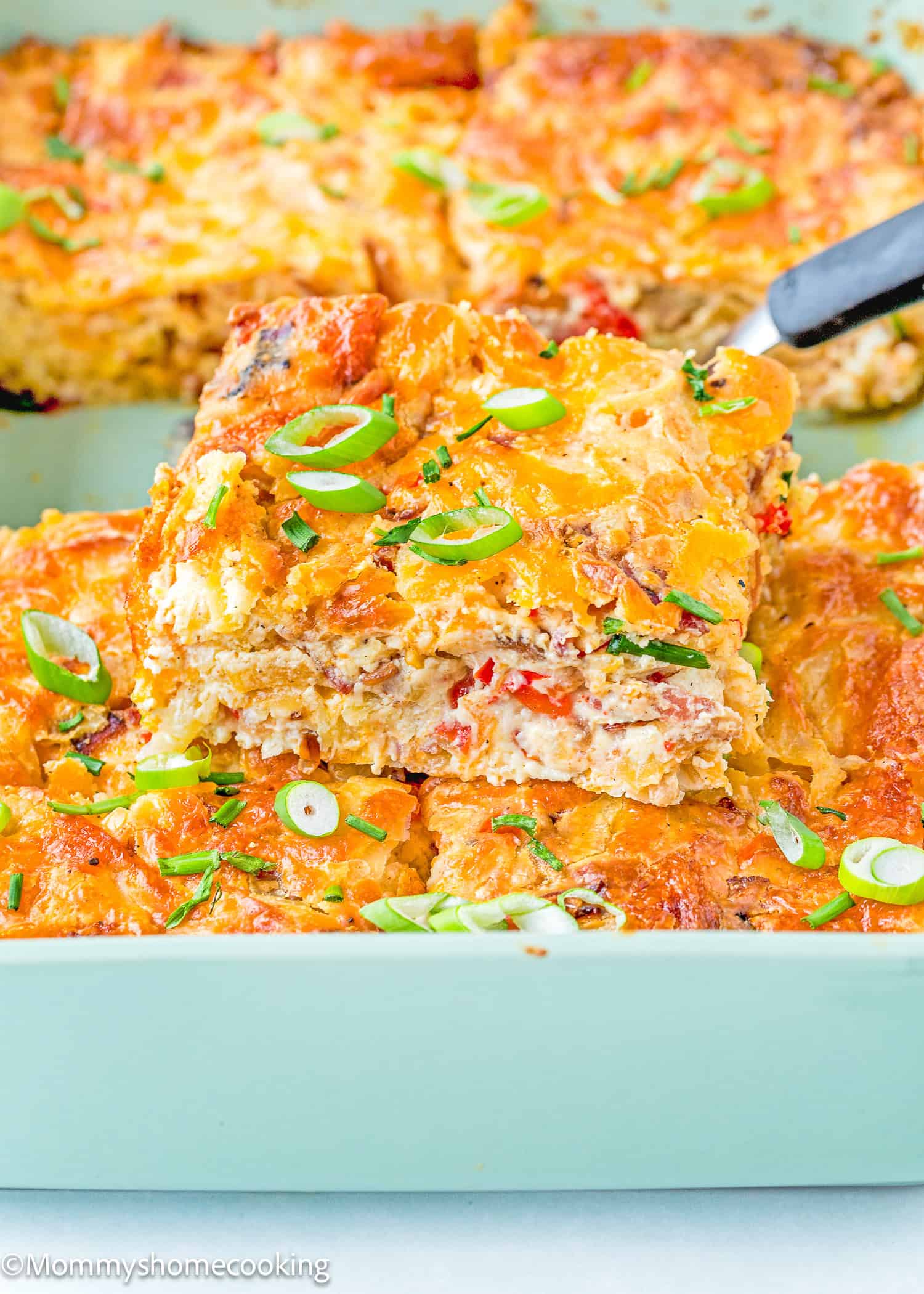 a slice of Breakfast Casserole Without Eggs on a green casserole dish.