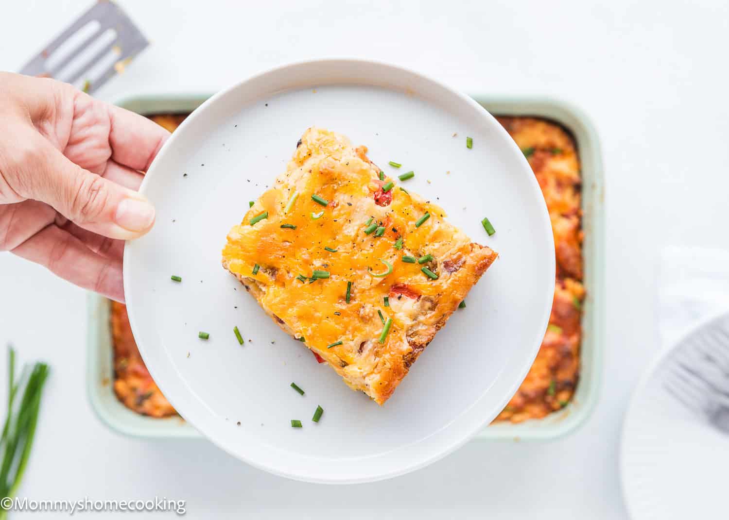 a woman hand holding a plate with a slice of Breakfast Casserole Without Eggs.