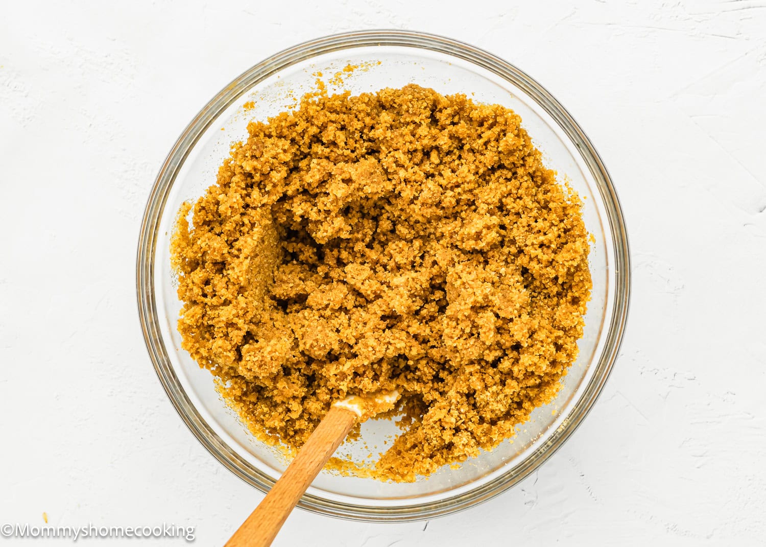 a graham cracker crust mixture in a bowl with a spatula.