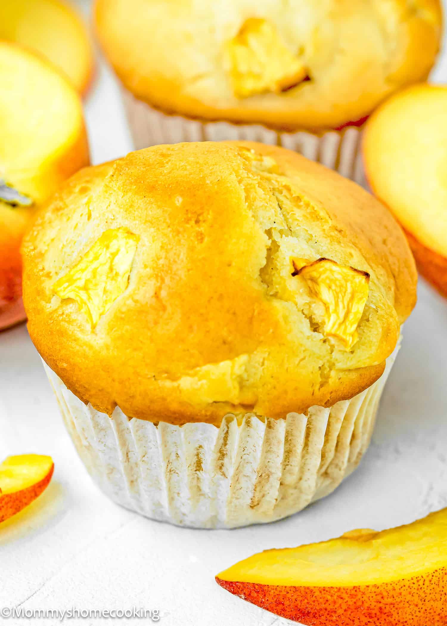 a Easy Peach Muffin made without eggs and dairy over a white surface.