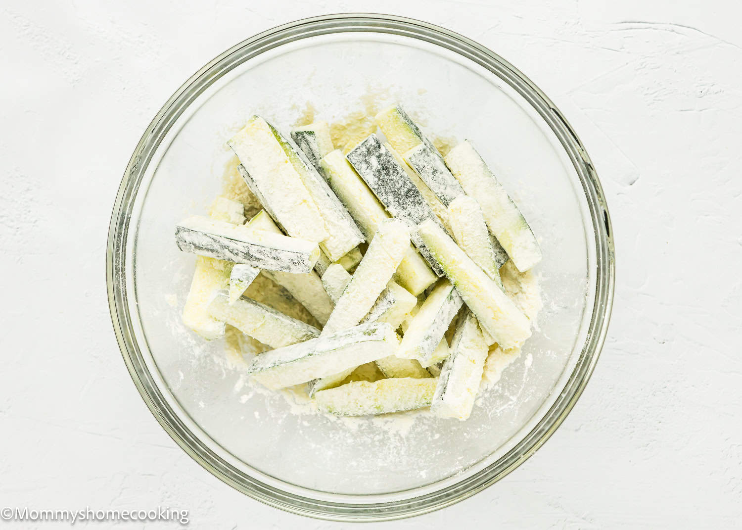 Zucchini sticks to make Eggless Zucchini Fries in a bowl with flour.