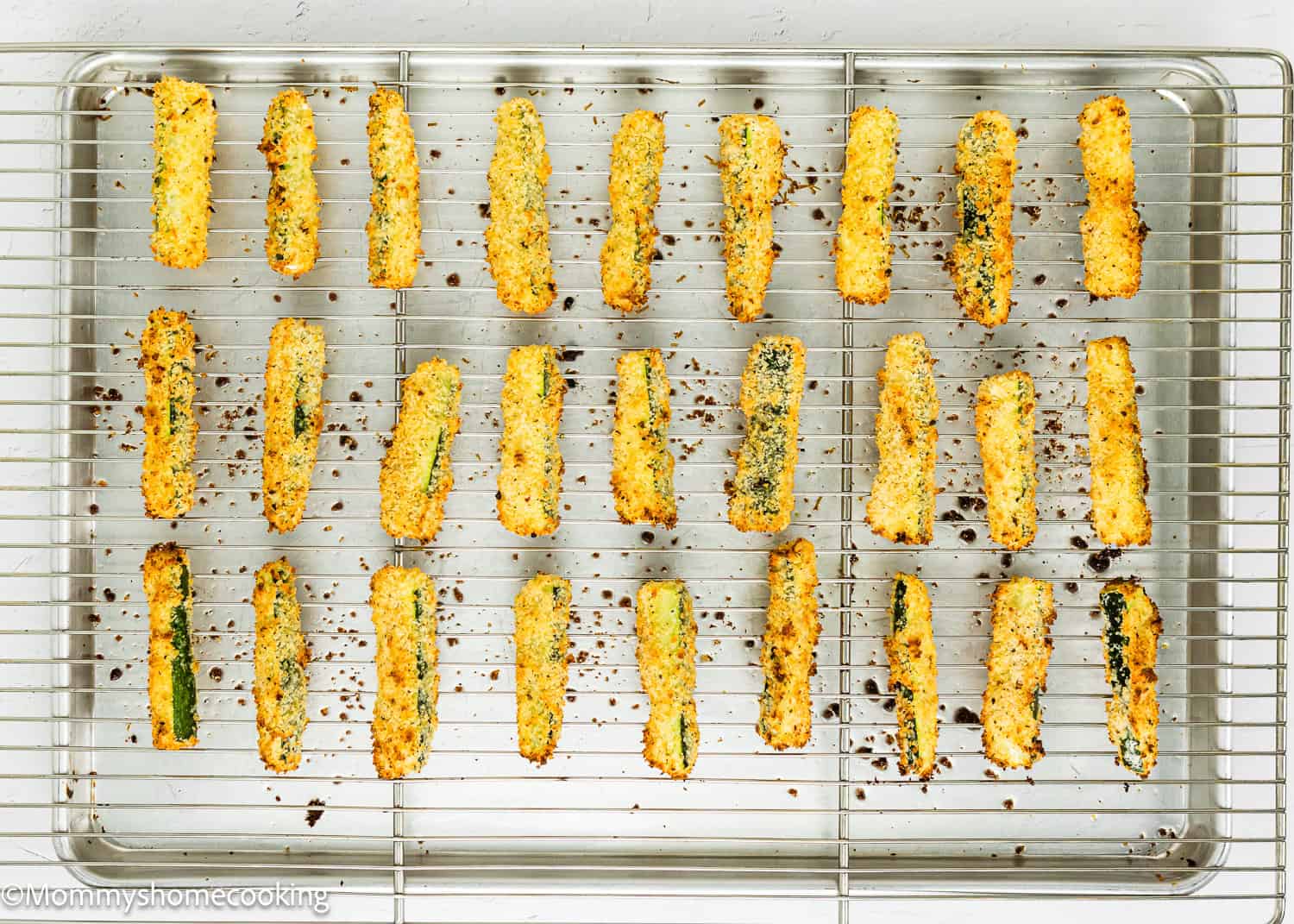 baked Eggless Zucchini Fries over a cooling rack on a baking sheet.