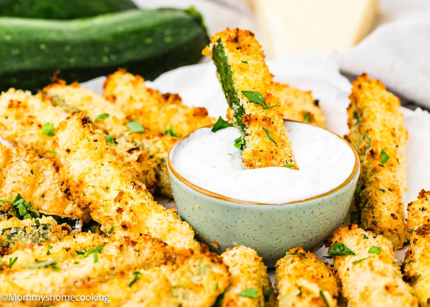 a Eggless Zucchini Frie dipped in a bowl with yogurt sauce.