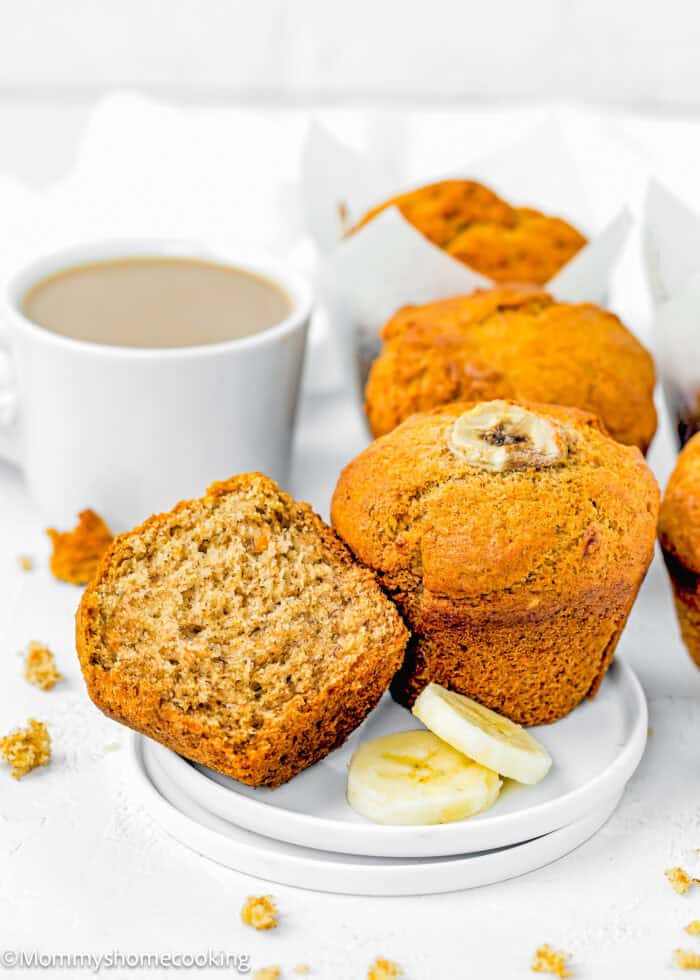 Healthy Easy Banana Muffins made with no eggs, dairy or sugar in a small plate with more muffins and a cup of coffee in the background.