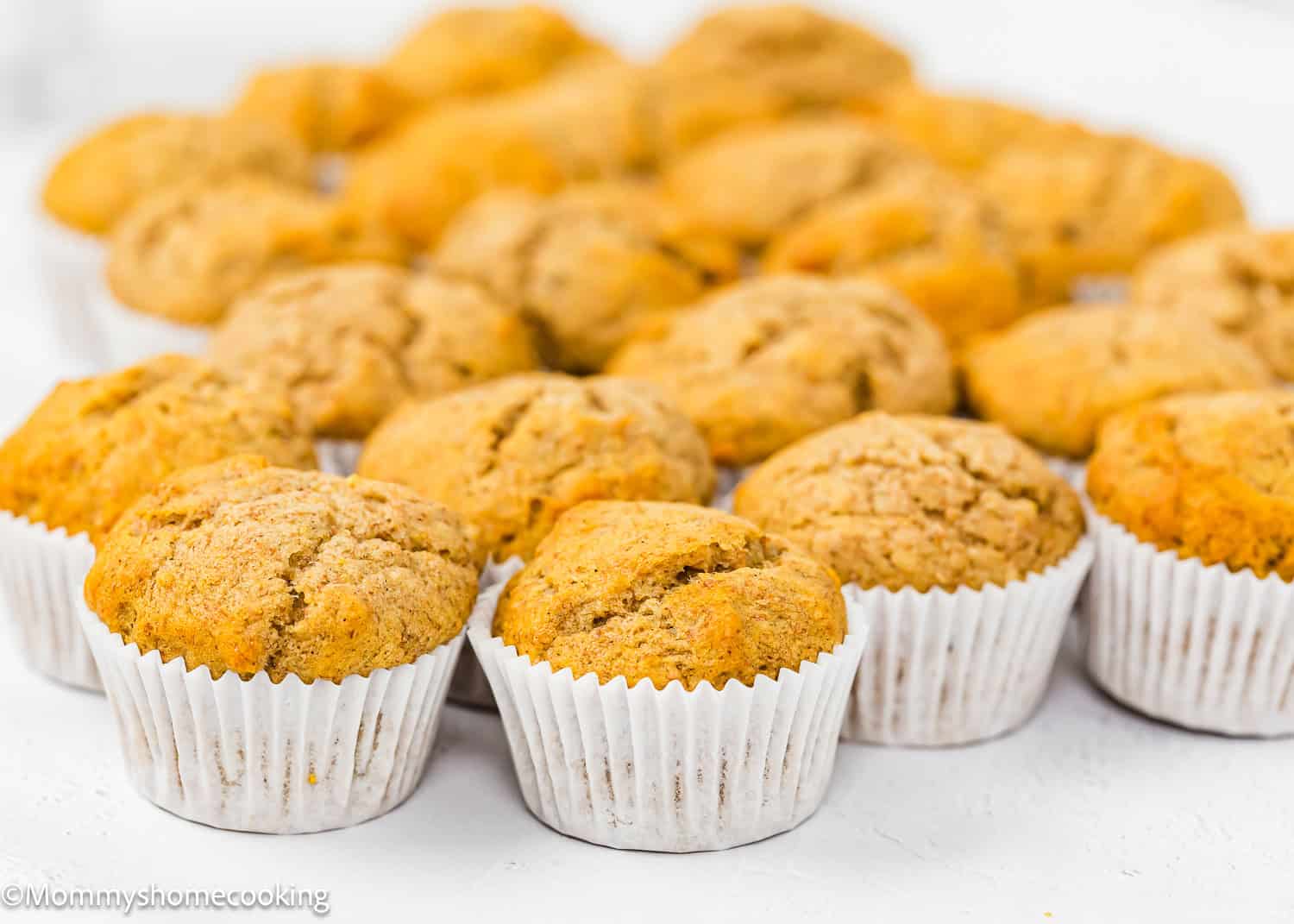 baked Healthy Mini Banana Muffins over a white surface.