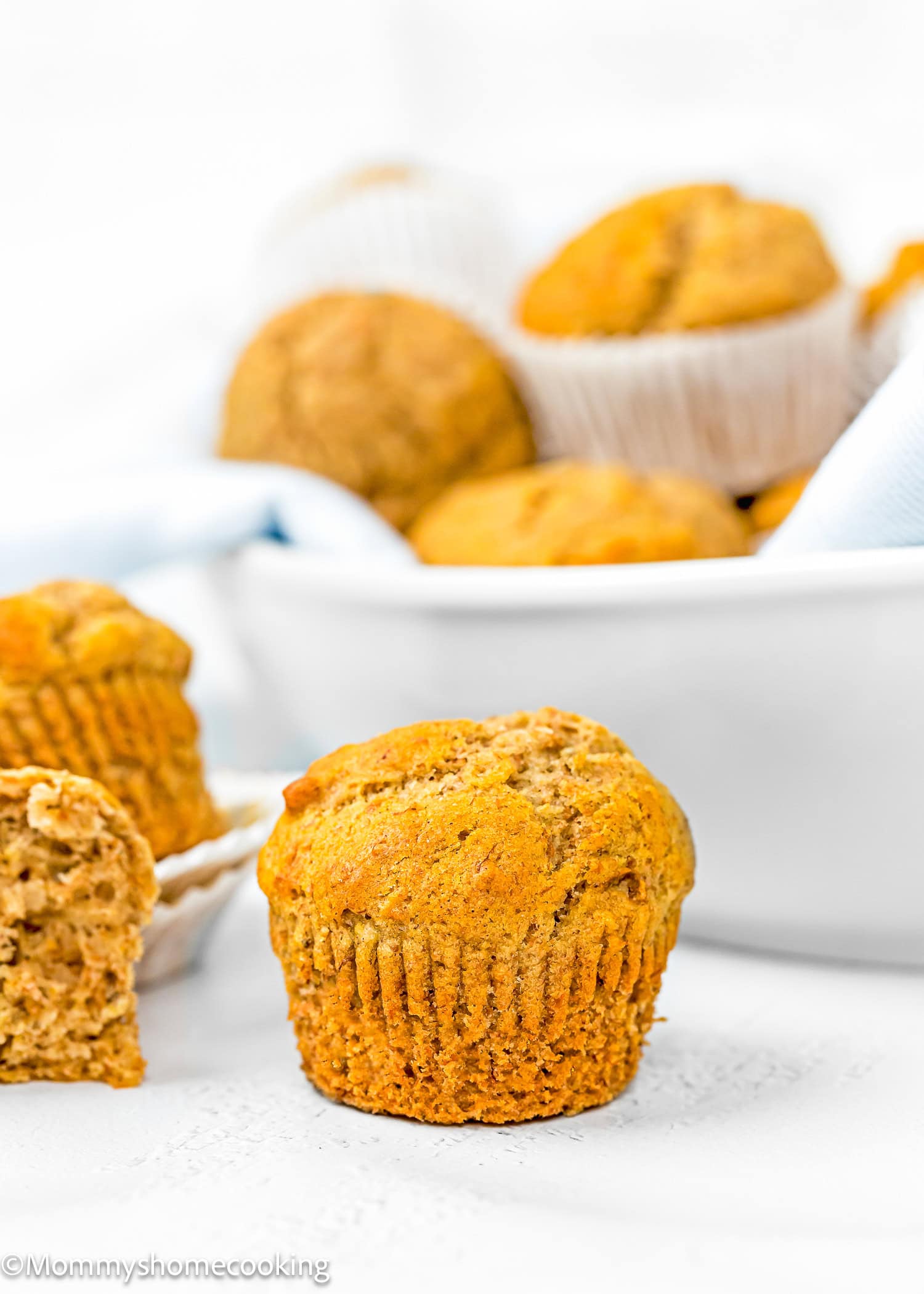 a Healthy Egg-Free, dairy-free and Vegan Mini Banana Muffin over a white surface with more muffins on the background.