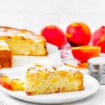slice of Easy Peach Cake made without eggs and dairy over a plate with a fork and the whole cake on the background.