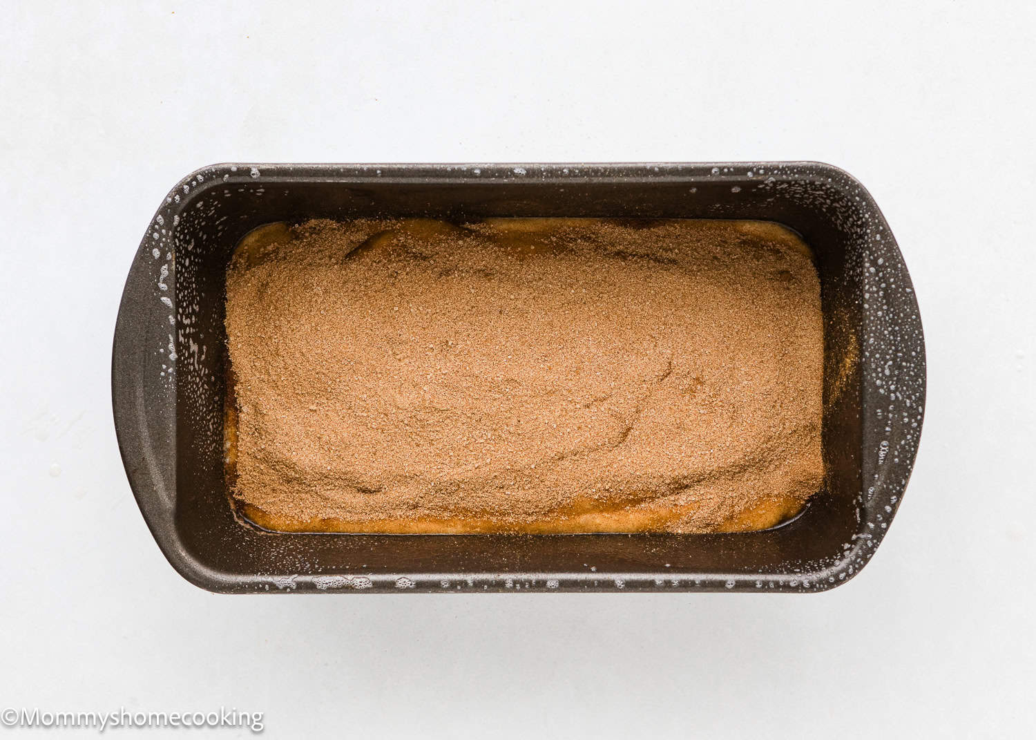 a whole unbaked Vegan Cinnamon Swirl Quick Bread batter with cinnamon-sugar on top in a loaf pan.