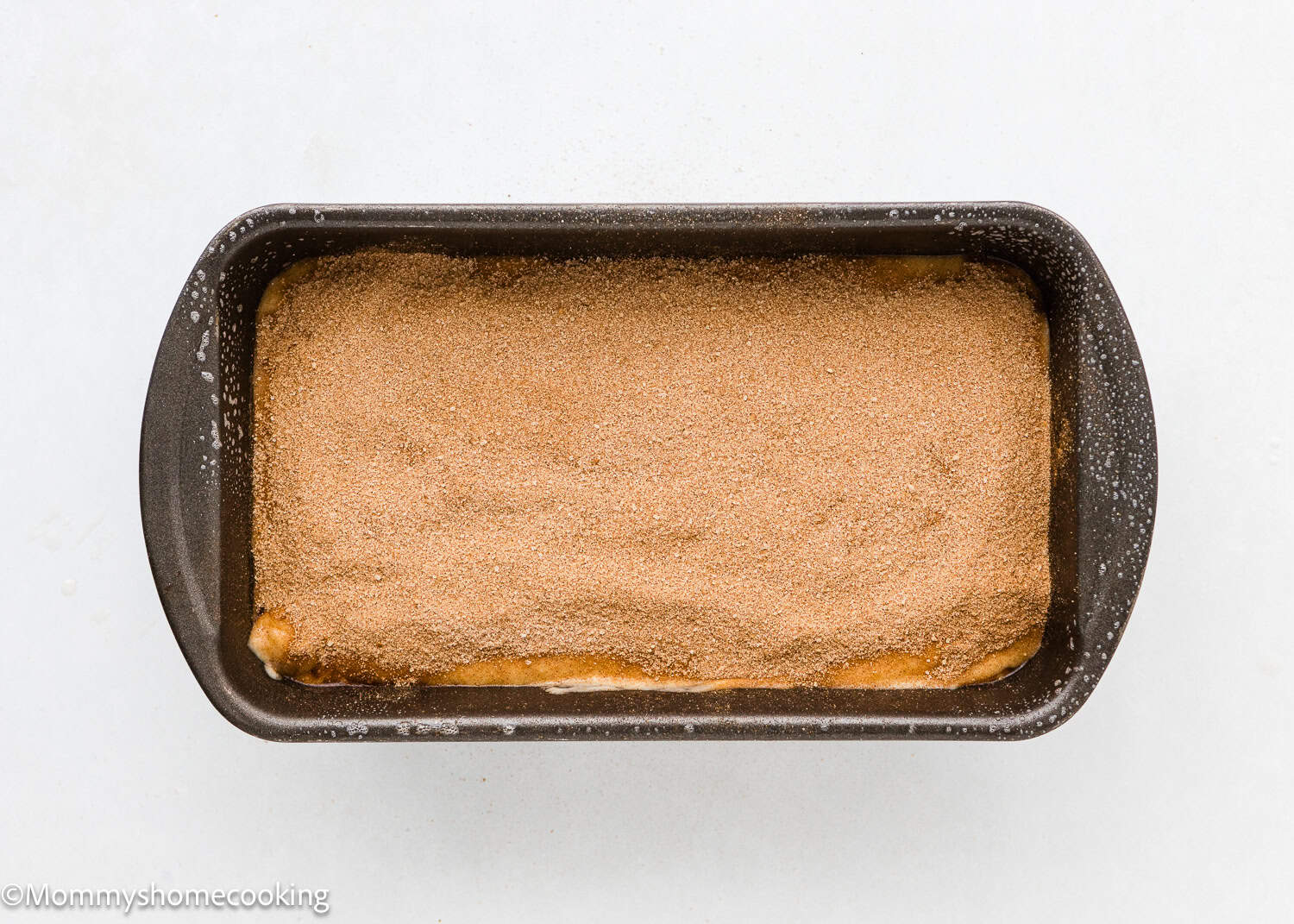 a whole unbaked Vegan Cinnamon Swirl Quick Bread with cinnamon-sugar on top in a loaf pan.