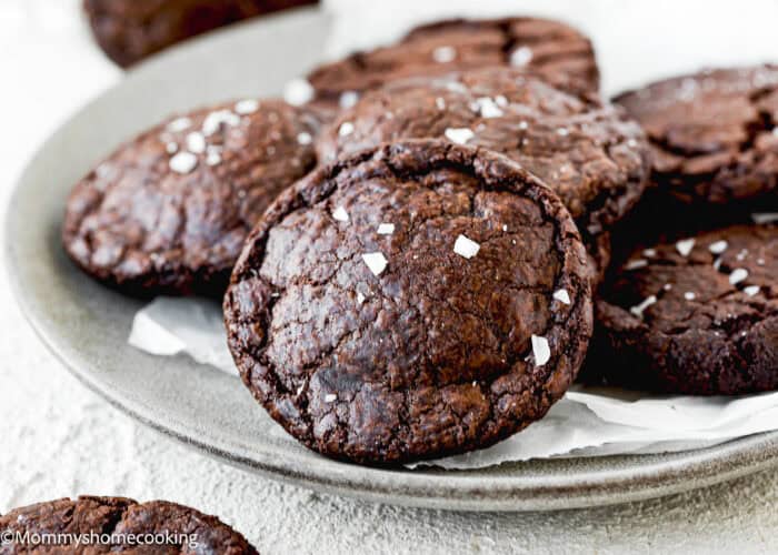 A plate of Best Eggless Brownie Cookies topped with sea salt flakes, arranged on parchment paper.