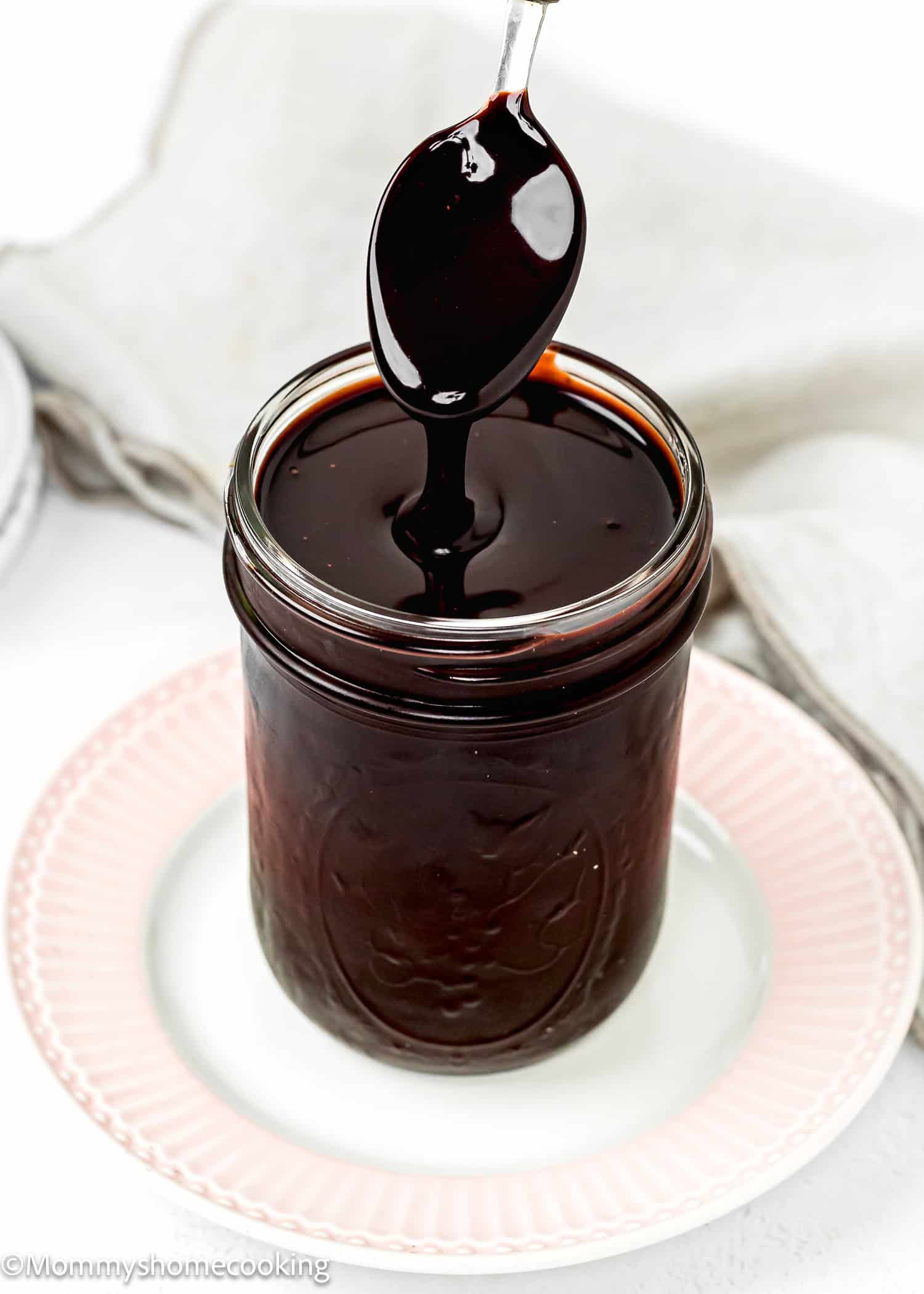 Easy Chocolate Hot Fudge Sauce in a glass jar with a spoon.