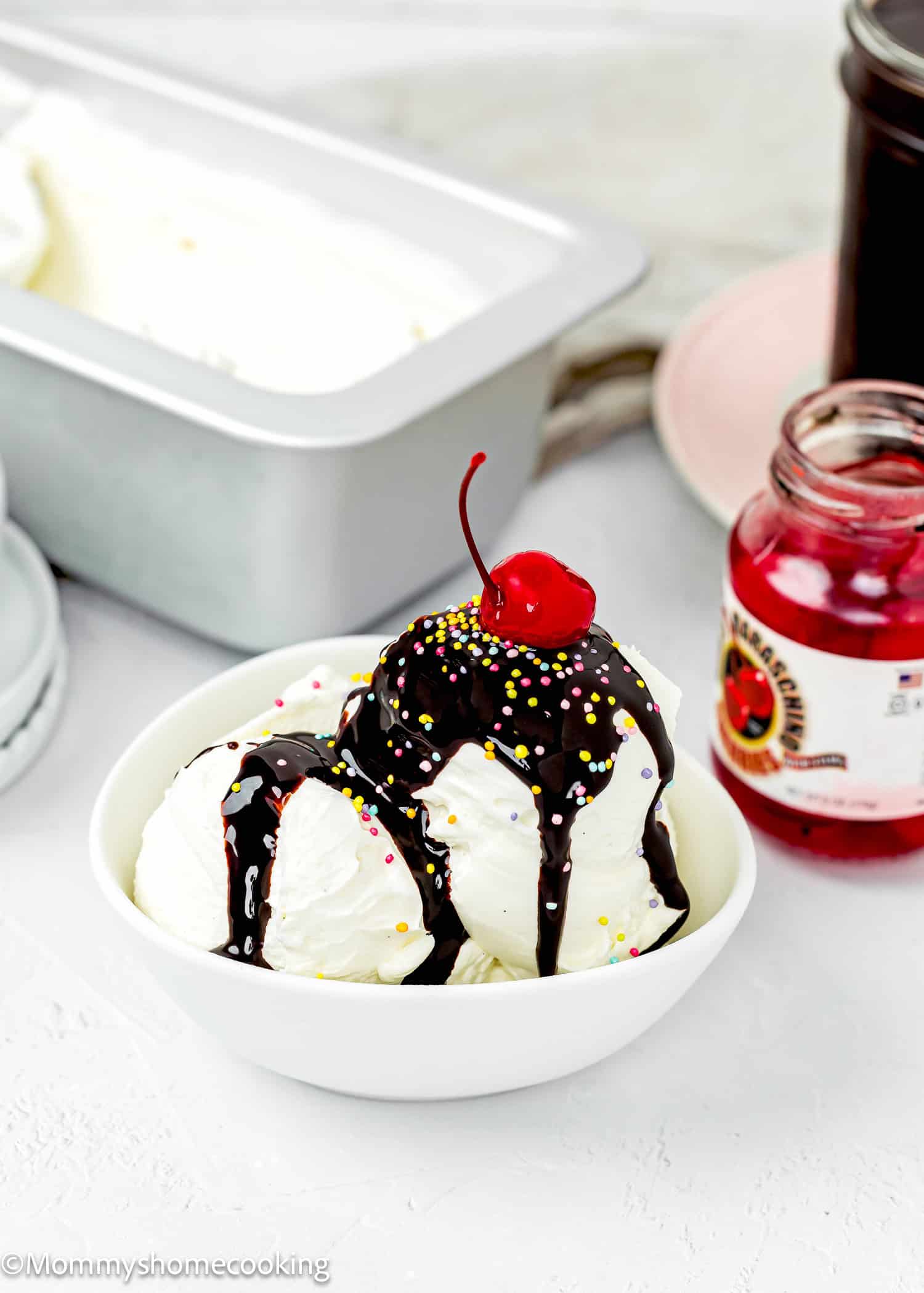 Easy Chocolate Hot Fudge Sauce over eggless homemade vanilla ice cream with sprinkles and a cherry.