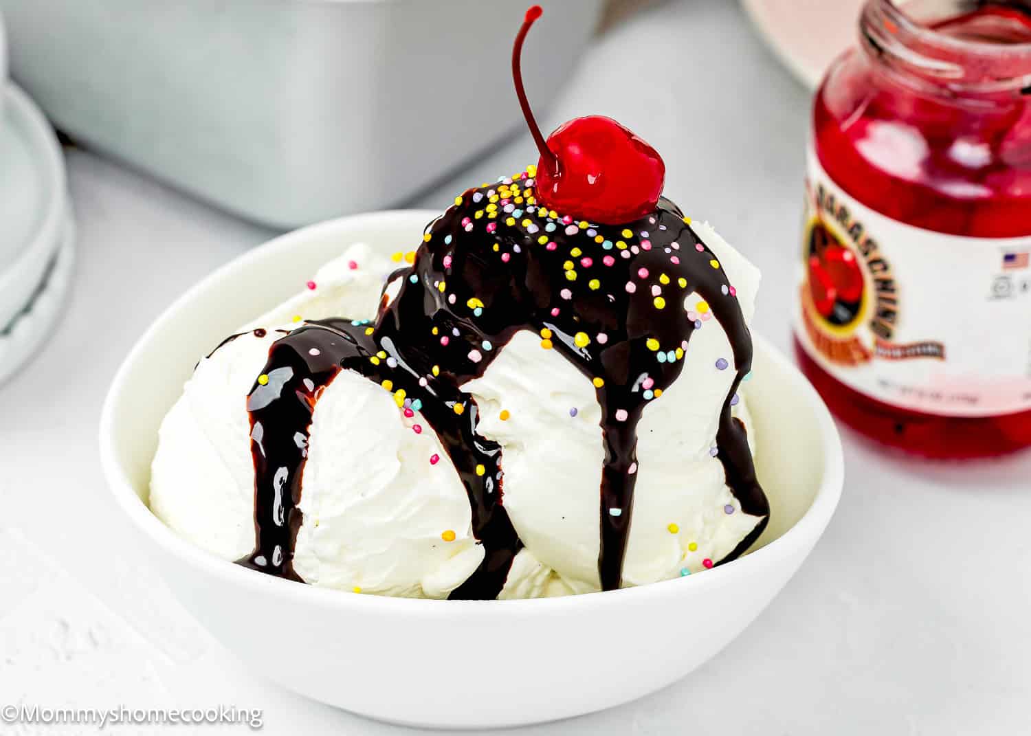 homemade Chocolate Hot Fudge Sauce over vanilla ice cream and a cherry and sprinkles.