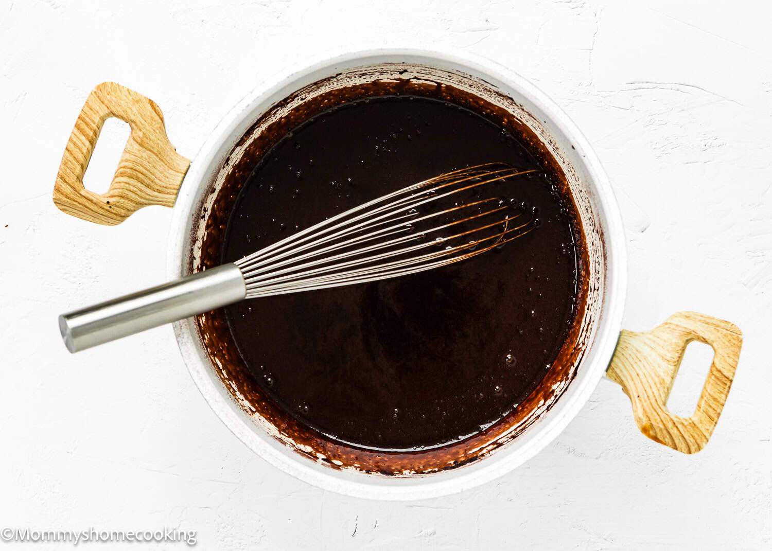 homemade Chocolate Hot Fudge Sauce in a pot with a whisk.