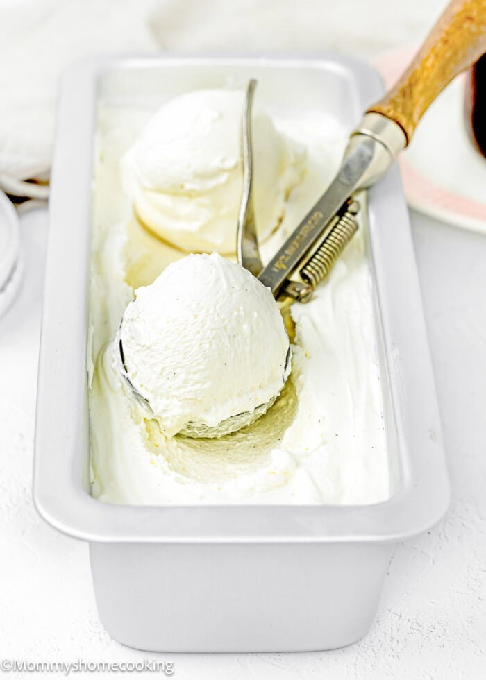 Egg-Free Homemade Vanilla Ice Cream in a loaf mold with a ice cream scoop in it.