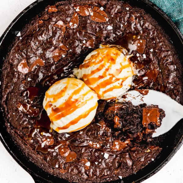 baked Easy Skillet Brownie made without eggs with salt flakes on top with ice cream on top and a serving spoon.