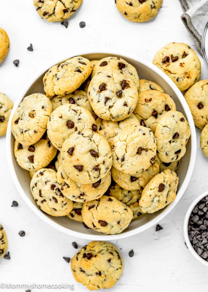 Easy Mini Chocolate Chip Cookies (Egg-Free) in a white bowl over a white surface with more cookies around it.