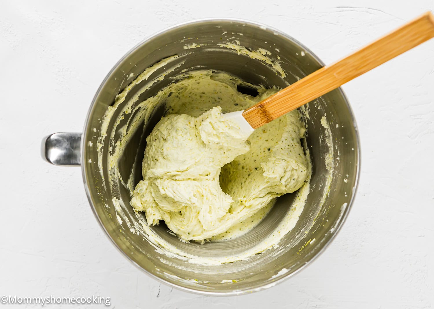 Pistachio buttercream in a stand mixer bowl with a spatula.