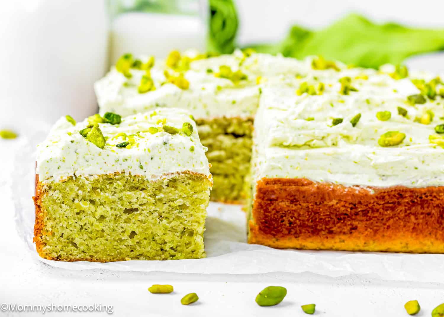 a Easy Pistachio Cake made without eggs showing its perfect fluffy inside texture over a piece of parchment paper.