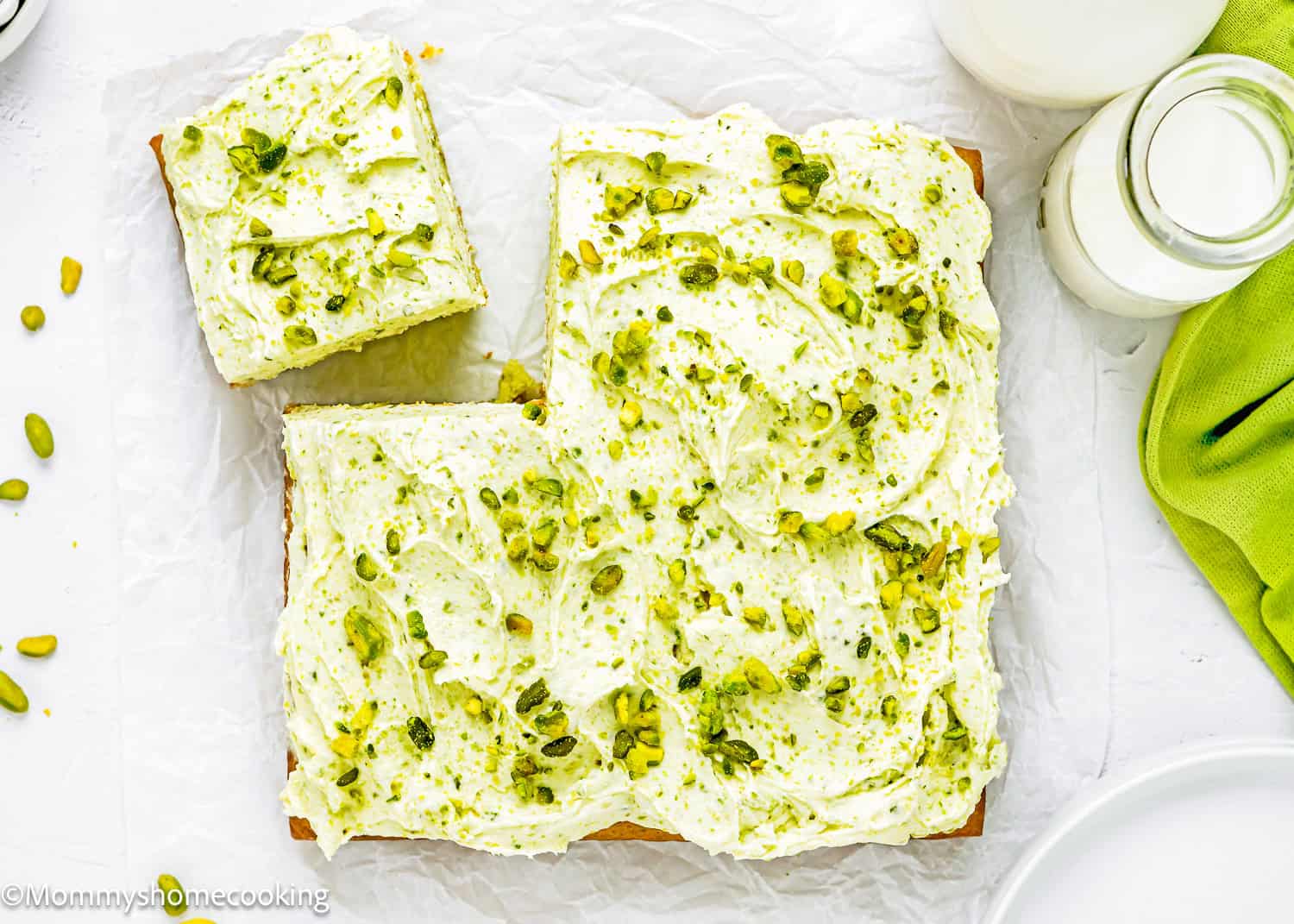 Egg-Free Easy Pistachio Cake frosted with pistachio buttercream over a piece of parchment paper.