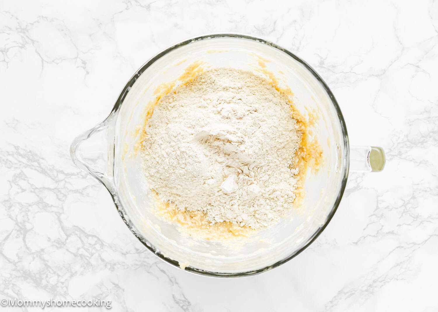 Eggless Brown Butter Banana Bundt Cake batter with flour in top in a stand mixer bowl.