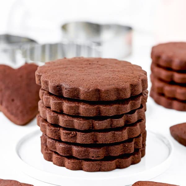 stack Eggless Chocolate Sugar Cookies over a white plate with more cookies around.