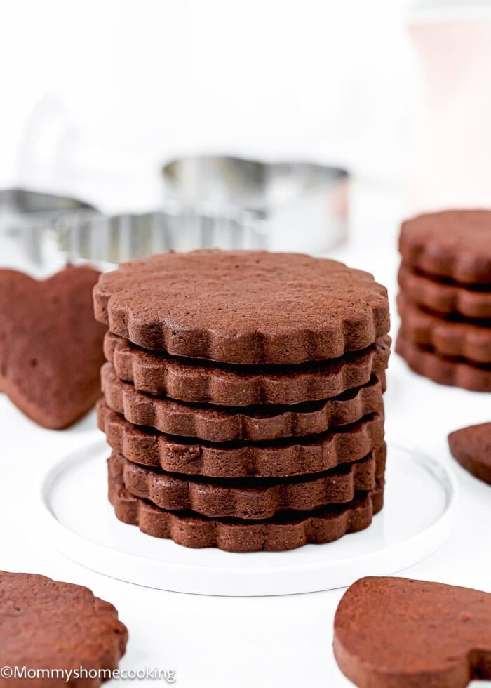 stack Eggless Chocolate Sugar Cookies over a white plate with more cookies around.