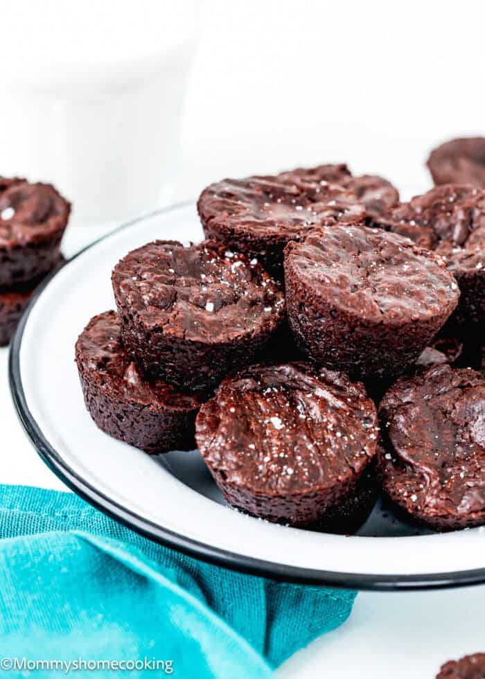 overhead view of a plate with Eggless Easy Brownies Bites and a blue kitchen towel on the side and a glass of milk in the background.