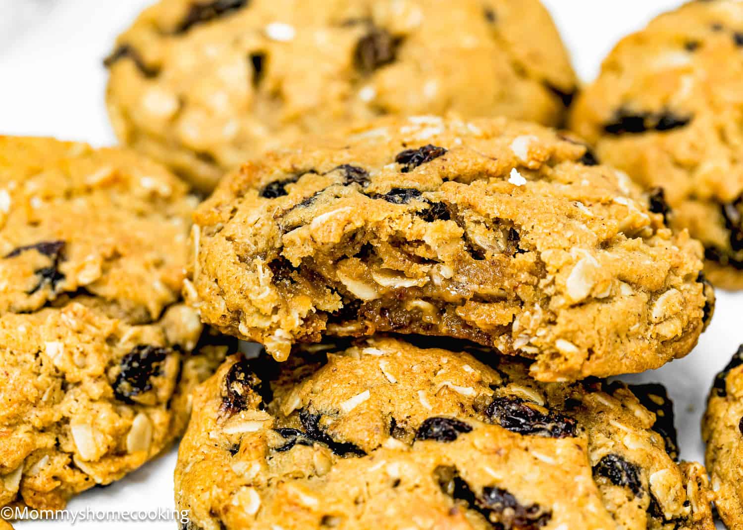 Close-up of Eggless Oatmeal Raisin Cookies, with one cookie partially broken to reveal a chewy interior. These easy-to-make treats come together in just one bowl.