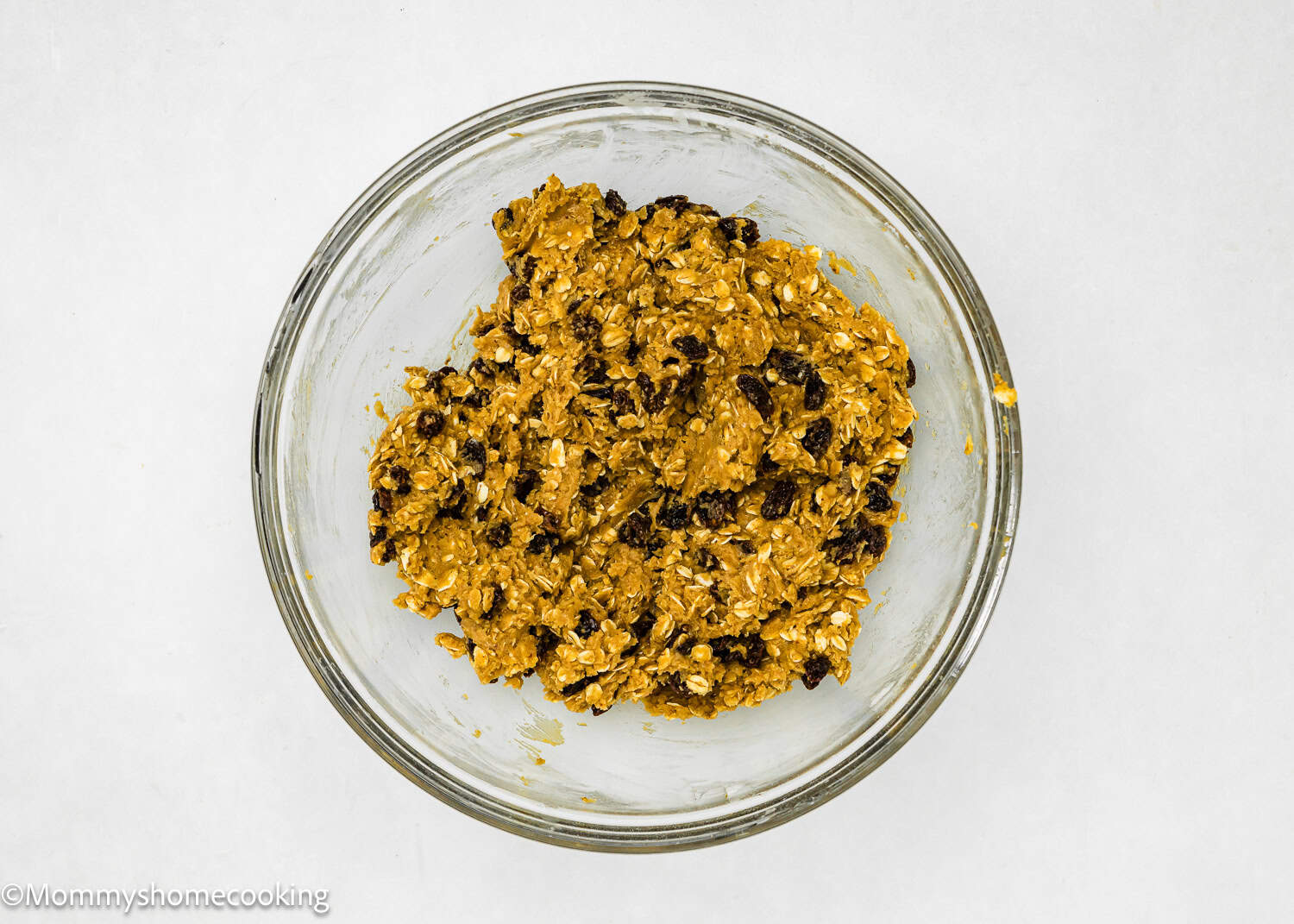 A glass bowl filled with eggless oatmeal raisin cookies dough.