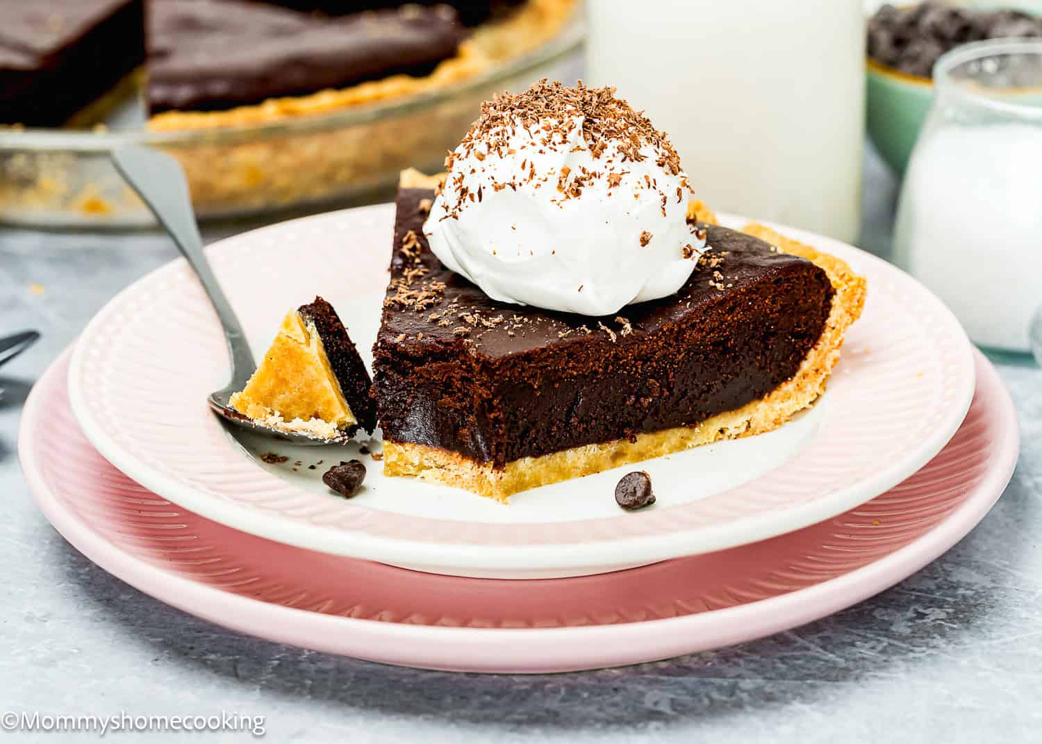 Slice of chocolate pie with whipped cream on a pink plate, garnished with chocolate shavings and accompanied by a fork. Made with an Easy Press In Pie Crust, this quick dessert is perfect for satisfying your sweet tooth without any chill time needed.