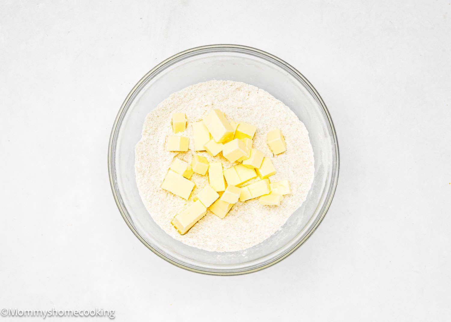 A bowl with flour and cubes of butter sits on a white surface, ready for creating the No-Fuss Easy Press In Pie Crust—no chill time needed.