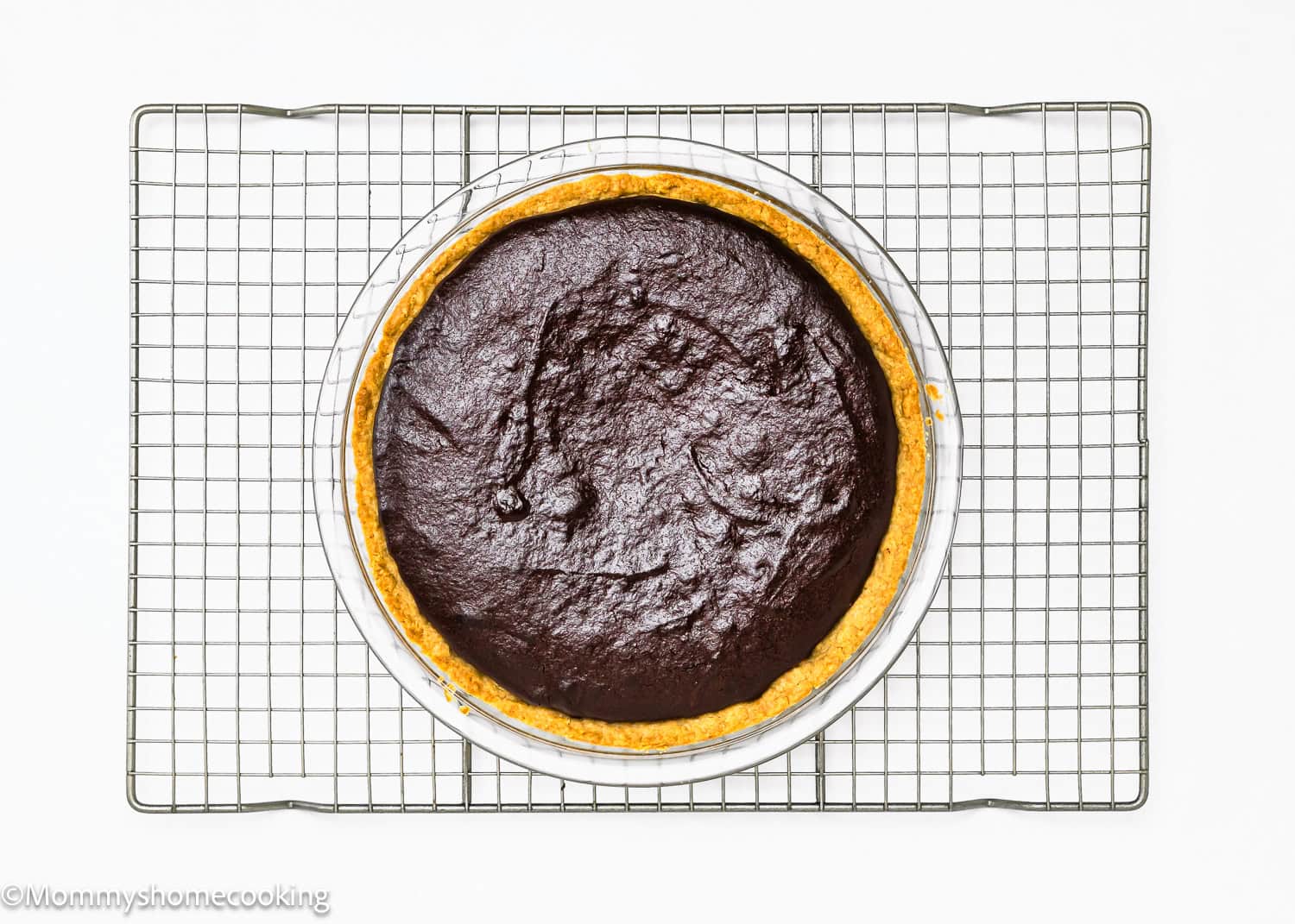 An beaked eggless brownie pie rests on a cooling rack, its rich chocolate hues inviting indulgence from above.