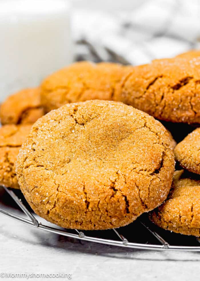 Close-up of freshly baked eggless gingersnaps cookies stacked on a cooling rack.