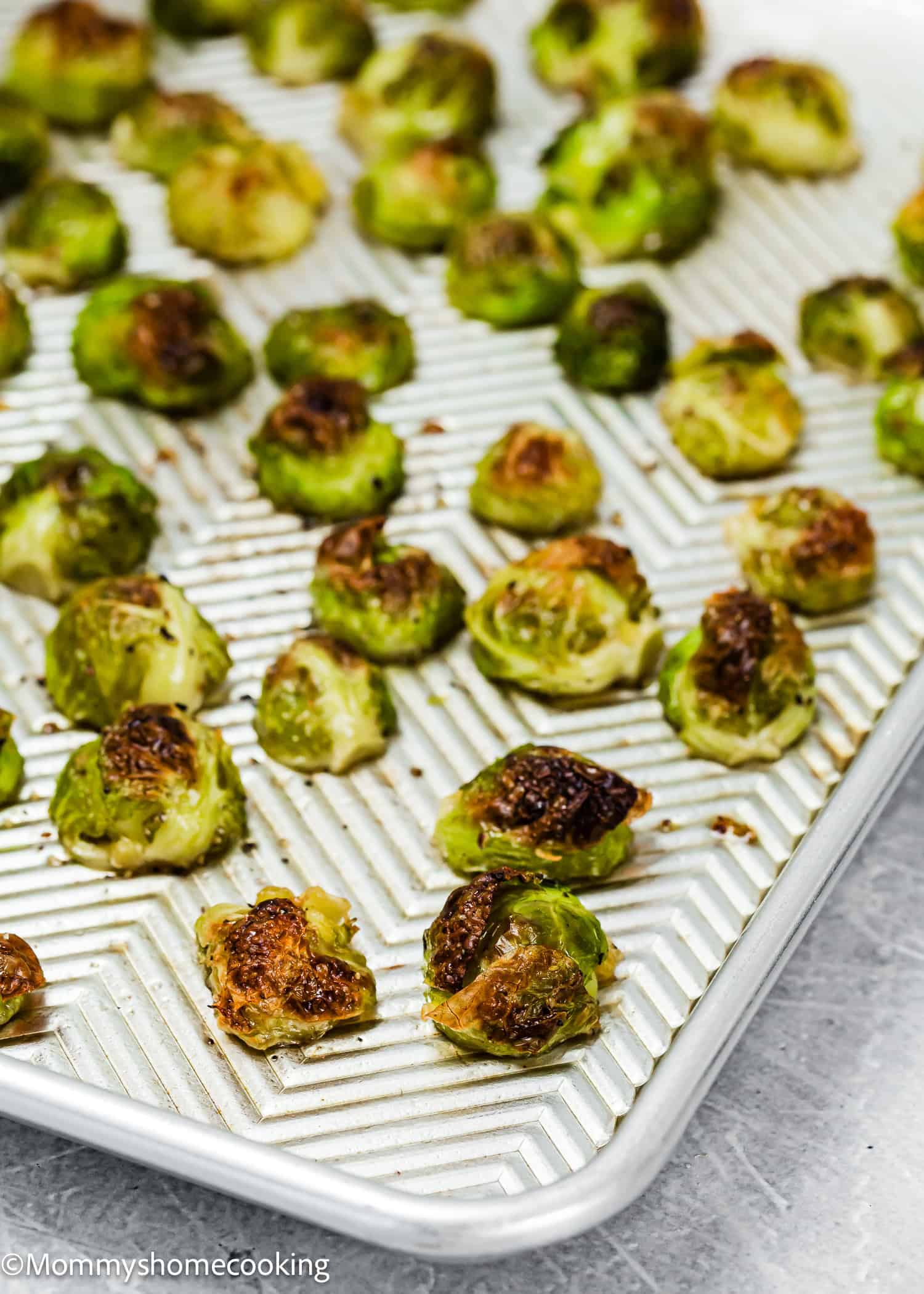 Easy Maple Roasted Brussels sprouts on a patterned baking sheet, lightly browned and evenly spaced, offer a perfect blend of sweetness and crispiness.