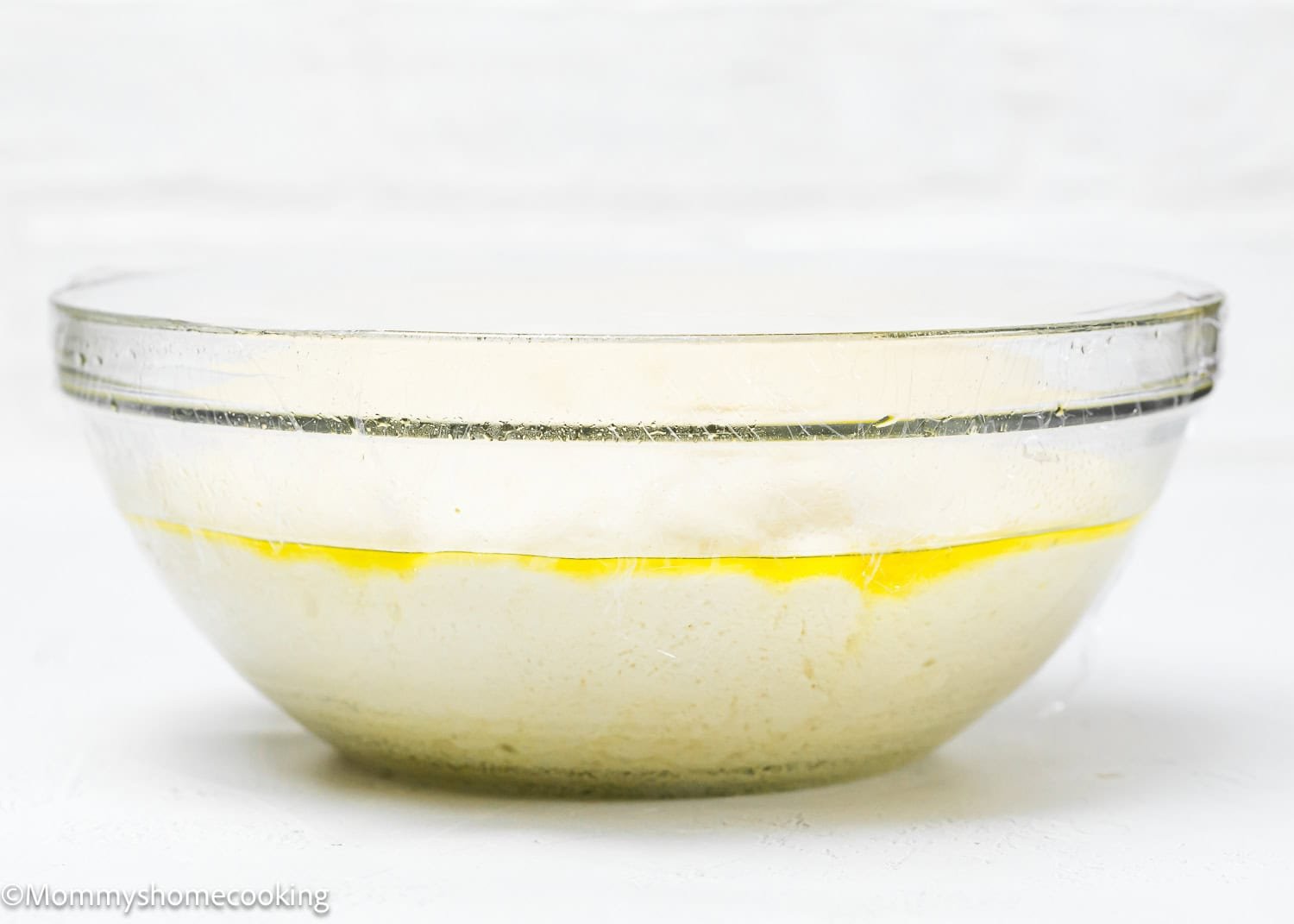 A glass bowl holds rising dough, enticing with its simplicity. Though covered in plastic wrap and topped with a sheen, this creation is a step away from quick and easy breadsticks that are egg-free and dairy-free, promising delicious results without the fuss.