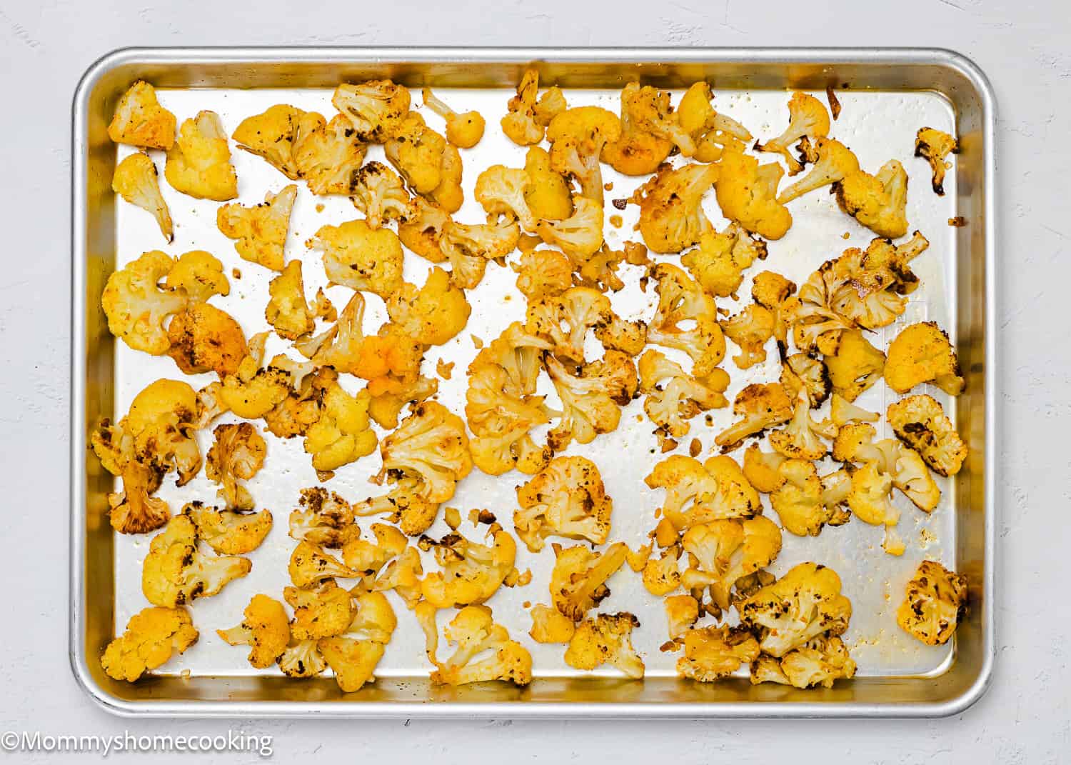 Quick and Easy Roasted Cauliflower florets spread on a metal baking sheet.